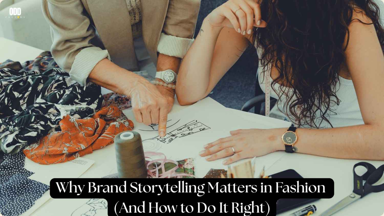 Reviewing a sketch with fabric samples and sewing tools on a table, illustrating brand storytelling in fashion.