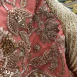 Close-up of intricate gold and rose-gold floral beadwork and sequin embroidery on pink fabric