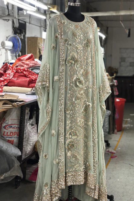 Mint green embroidered ethnic dress with intricate floral detailing and embellished borders displayed on a mannequin