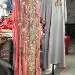 Pink embroidered ethnic dress and grey kurta displayed on mannequins in a garment workshop